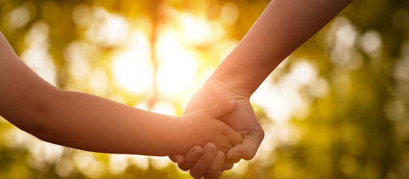 imagen de mano de padre e hijo con sol detrás